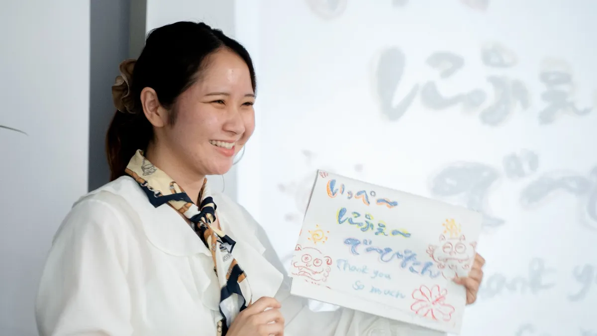 手描きの「Thank you」のボードを持ち、笑顔で発表する参加者